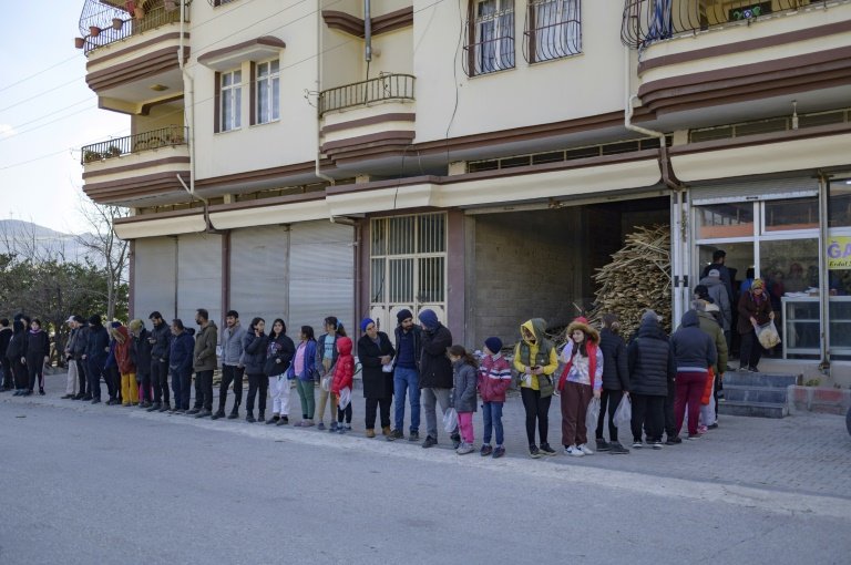 Residents wait in a queue outside a bakery giving out free bread. — AFP