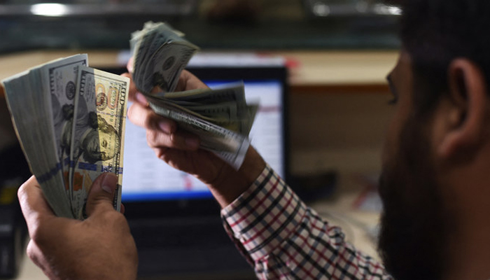 A Pakistani dealer counts US dollars at a currency exchange shop in Karachi on October 9, 2018. — AFP