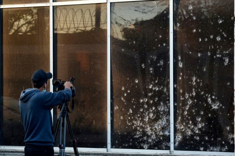 A news cameraman films the shrapnel-riddled glass outside the Karachi Police Office compound. — AFP