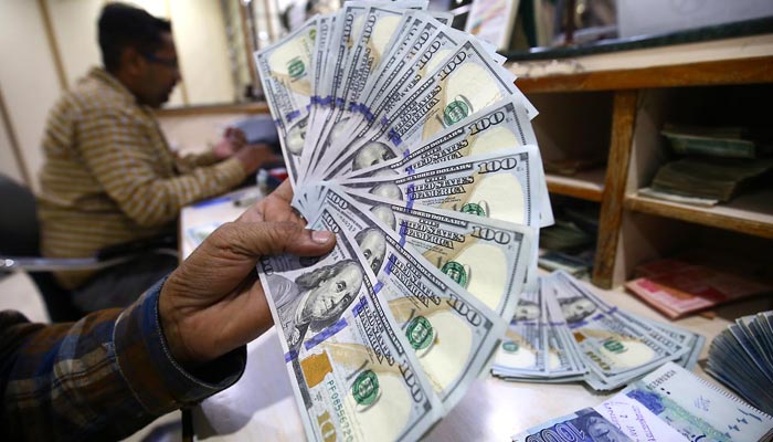 Foreign currency dealer selling US dollar bills at a money exchange company in Karachi on January 10, 2023. — INP