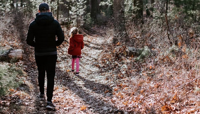 A man and his daughter are seen walking a trail together. Representational image by Unsplash