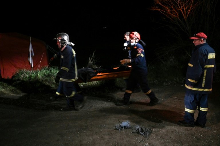 Rescue workers carry a body they pulled out of the wreckage after a train accident in the Valley of Tempi near Larisa, Greece. — AFP