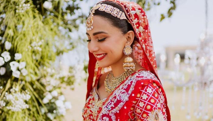 Pakistani actress Ushna Shah poses for the camera on her wedding day in a bright red lehnga. — Instagram/@wardhasaleemofficial