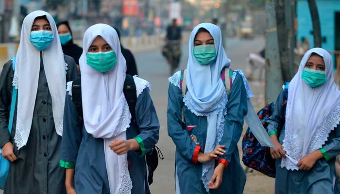 Yüz maskesi takan öğrenciler 15 Eylül 2020'de bir sokaktan okullarına yürüyorlar. — AFP