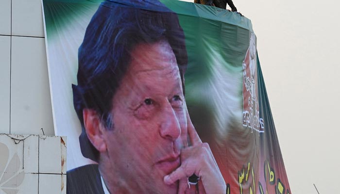 Policemen stand guard above a giant portrait of former prime minister Imran Khan during an anti-government rally in Rawalpindi on November 26, 2022. — AFP