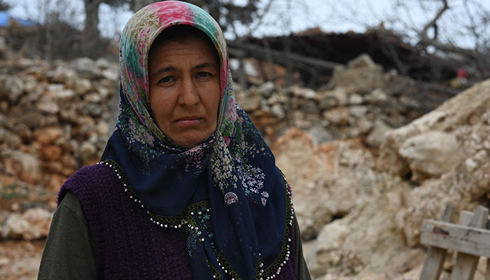 Sennur Sutdelisi, 37, who lost her two teenage chlidren and husband in the quake, poses outside her destroyed home in the village of Buyuknacar, near Pazarcik, Kahramanmaras province, on March 5, 2023, one month after a massive earthquake struck southeast Turkey.— AFP