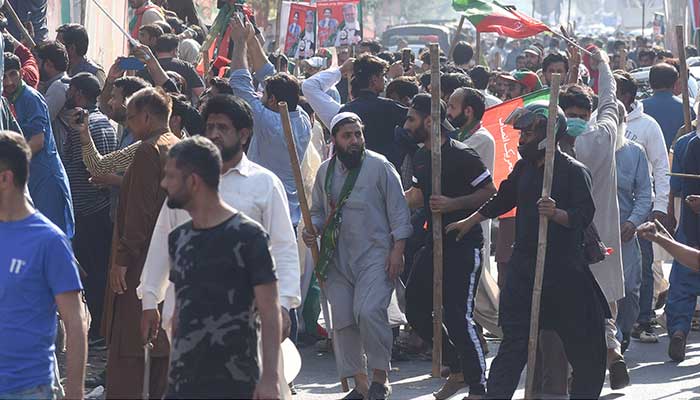 PTI workers hold sticks during a rally at Zaman Park, Lahore. — Online