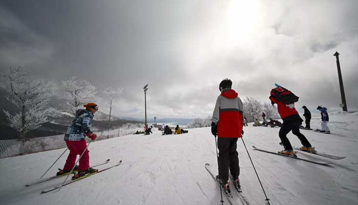 Kayakçılar ve snowboardcular, Inawashiro Gölü'ne bakan bir kayak kursunda toplanıyor.  — AFP/Dosya