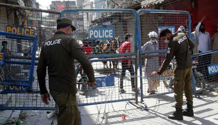 A representational image of policeen standing behind roadblocks in Punjab. — APP