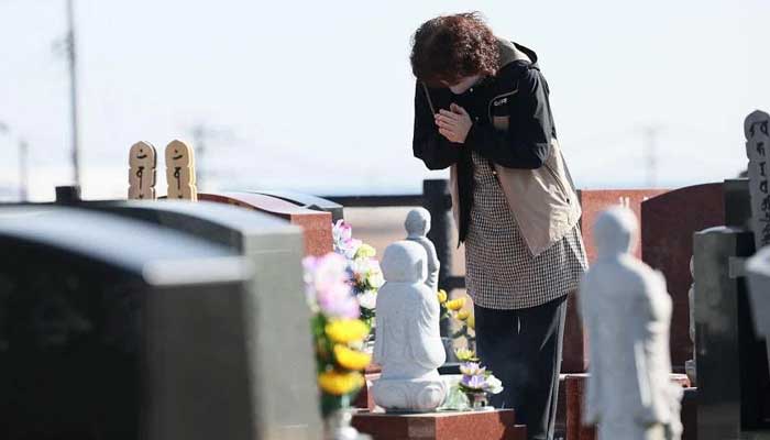 Bir yaslı, 11 Mart 2023'te Japonya'nın Namie kentindeki bir mezarlıkta Büyük Doğu Japonya Depremi kurbanları için dua ediyor. — AFP