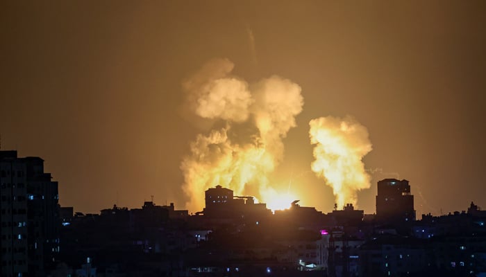 İsrail'in 5 Ağustos 2022'nin sonlarında Gazze Şehrindeki bir binaya düzenlediği hava saldırılarının ardından duman ve ateş yükseliyor. — AFP