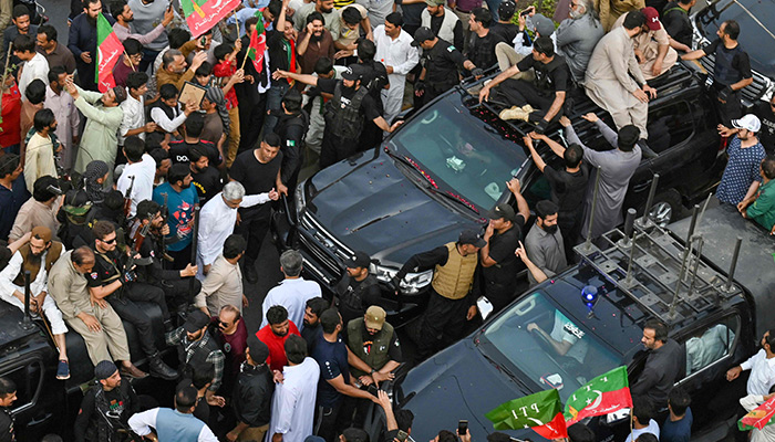 Security personnel and supporters escort a vehicle (left) carrying former prime minister Imran Khan during an election campaign rally for Punjabs provincial assembly to be held next month, in Lahore on March 13, 2023. — AFP/ File