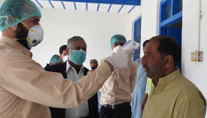 A doctor checks the temperature of a man returning from Iran at a quarantine zone to test for the COVID-19 coronavirus in the Pakistan-Iran border town of Taftan in February. — AFP/File