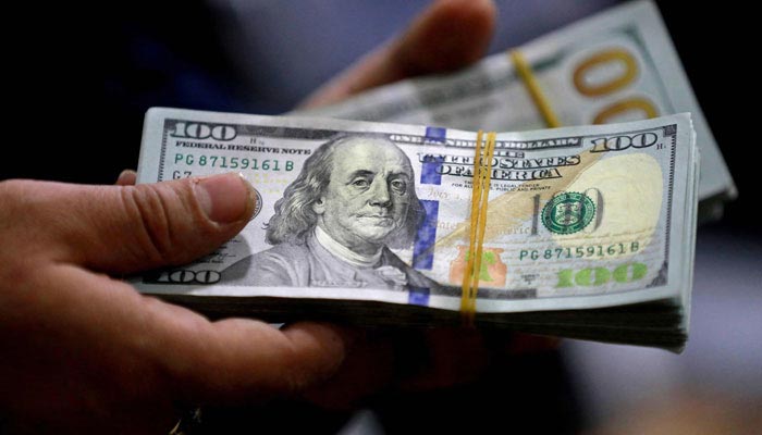 An undated image of a person holding a $100 stack. — AFP/File