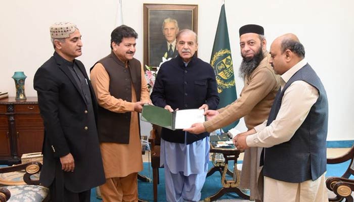 Prime Minister Shehbaz Sharif hands over the allotment letter of a residential plot to the heirs of Qazi Abdur Rehman Amritsari. — Twitter/@HamidMirPAK