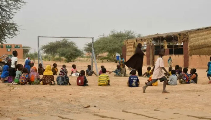 A teacher and her pupils play in a yard at a school near a site for displaced people on the outskirts of Ouallam, Niger in October 2022. AFP/File