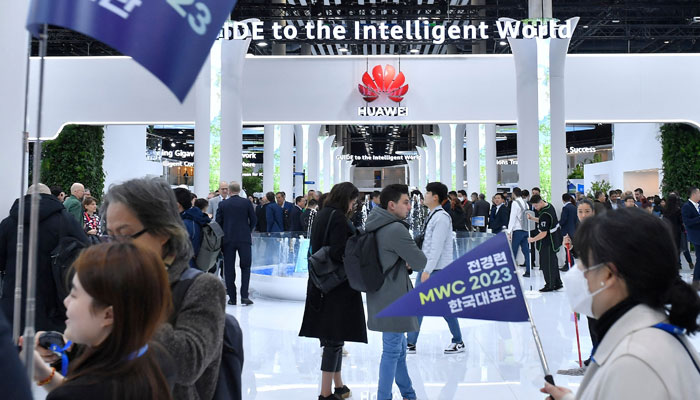 Pengunjung berjalan di samping stan Huawei dari pabrikan China di Mobile World Congress (MWC), pertemuan tahunan terbesar industri telekomunikasi, di Barcelona pada 28 Februari 2023. — AFP