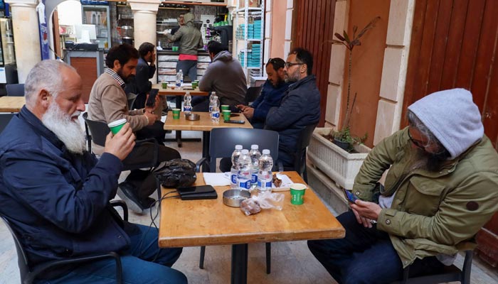 In this picture taken on March 16, 2023, men drink coffee outside a cafe in Tripoli. Italy left a deep cultural mark on Libya, the only Arab country it colonised: a national love of espresso. — AFP