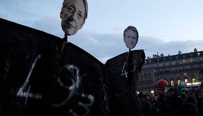 Protesters hold placards depicting French Prime Minister Elisabeth Borne (L) and French President Emmanuel Macron at Place de la Republique during a demonstration, a few days after the government pushed a pensions reform through parliament without a vote, using the article 49.3 of the constitution, in Paris on March 21, 2023. AFP
