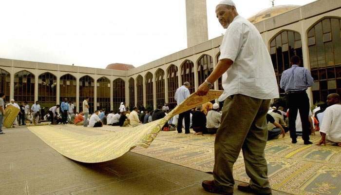 Man unfurls a prayer mat during Friday prayers at London Central Mosque. AFP/File
