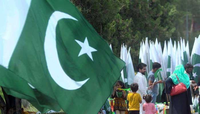 A family purchases national flag from a roadside stall in preparations of 75th Independence Day in Islamabad on August 13, 2022. — APP