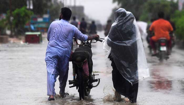 A family wades through a flooded street during a monsoon rainfall in Karachi on July 24, 2022. — AFP