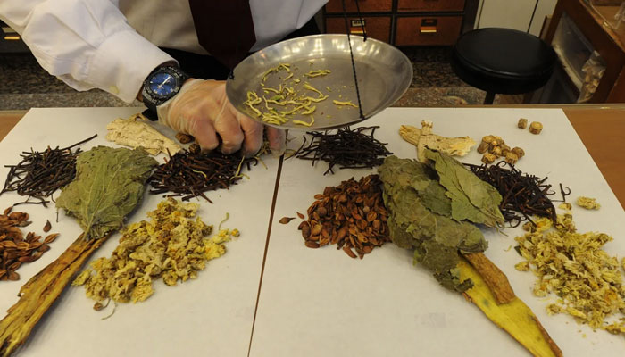 A worker at a Traditional Chinese Medicine store prepares various dried items in Hong Kong on December 29, 2010. — AFP