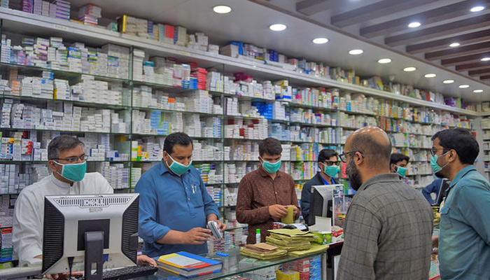 Pharmacy employees wearing facemasks as a preventive measure against the coronavirus attend to customers in Islamabad, Pakistan, on March 23, 2020. — AFP