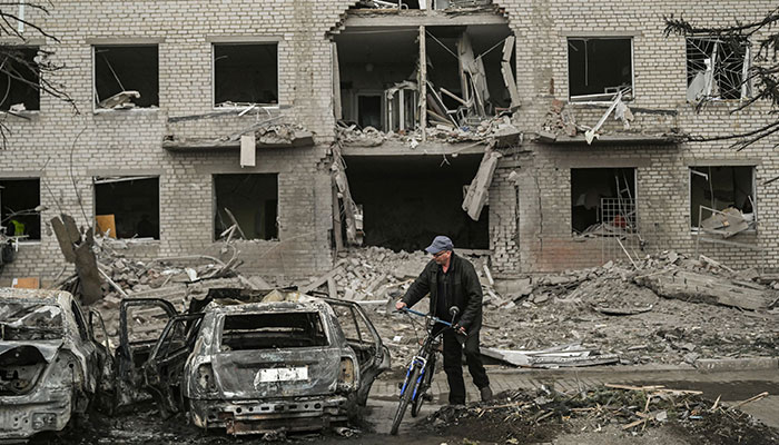 A man with his push bike stops to look at the remains of a destroyed vehicle in front of a destroyed building after a deadly strike in the city of Sloviansk, on March 27, 2023. Shelling of the eastern Ukraine town of Sloviansk on March 27, 2023, killed at least two people and wounded more than two dozen others, authorities said.—AFP