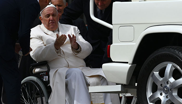 TOPSHOT - Pope Francis speaks with his aides prior to being helped get up the popemobile car from his wheelchair, as he leaves on March 29, 2023, at the end of the weekly general audience at St. Peter´s square in The Vatican. Pope Francis has been at the Gemelli Hospital in Rome since the afternoon of March 29, 2023, for some previously scheduled check-ups, the Holy See press director said.—AFP
