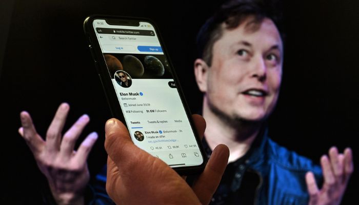 Image shows a picture of Elon Musk behind a mobile phone screen with his Twitter profile.— AFP/file