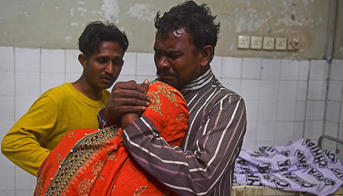 Relatives mourn beside the body of a victim who died in a stampede during a Ramadan alms distribution for people in need, at a hospital in Karachi on March 31, 2023. — AFP