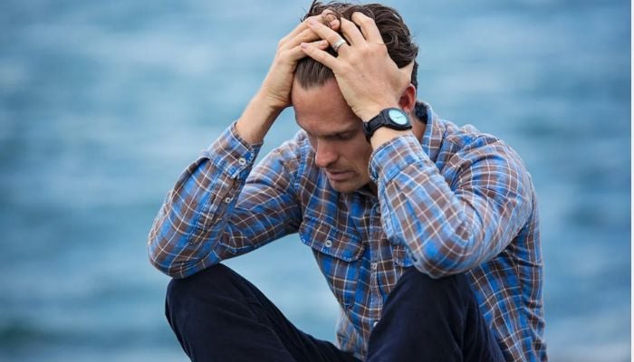 Man in blue and brown plaid dress shirt touching his hair.— Pexels