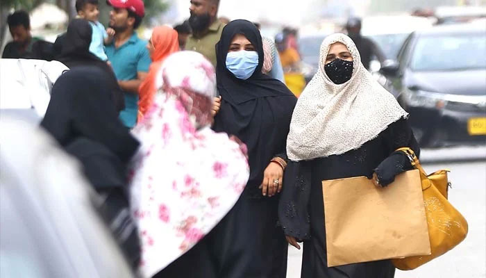 29 جون 2022 کو کراچی میں کورونا وائرس (COVID-19) کے کیسز میں اضافے کے درمیان خواتین بازار سے باہر چلتے ہوئے ماسک پہن رہی ہیں۔ - INP