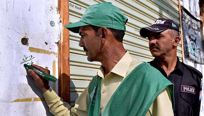 Enumerator marking completion of data collection at a building in Larkana during the first-ever digital population and housing census on March 18, 2023. — APP