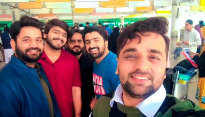 Pakistani students pose for a selfie at the airport. — APP