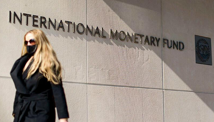 A woman walks past a building of the International Monetary Fund. — AFP/File