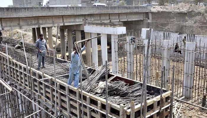 Labourers are busy in construction work of bridge. — APP/File