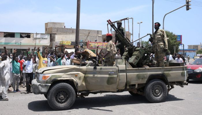 سوڈانی 16 اپریل 2023 کو بحیرہ احمر کے شہر پورٹ سوڈان میں آرمی کمانڈر عبدالفتاح البرہان کے وفادار فوجی سپاہیوں کو سلام کر رہے ہیں۔ اے ایف پی