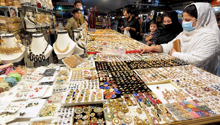Kadınlar, 18 Nisan 2023'te Peşaver'de Ramazan Bayramı'na hazırlanırken takı seçip satın alıyor. — APP