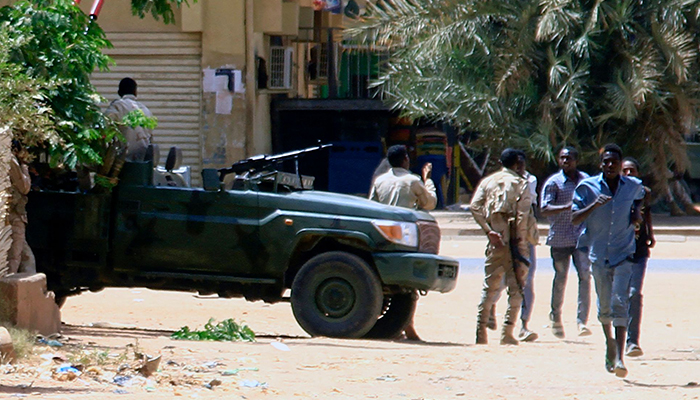 15 Nisan 2023'te Hartum'da insanlar bir askeri aracın yanından geçiyor. — AFP