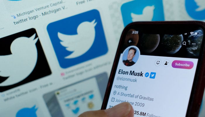 This illustration shows Elon Musks blue tick next to his name on a smartphone. — AFP/File