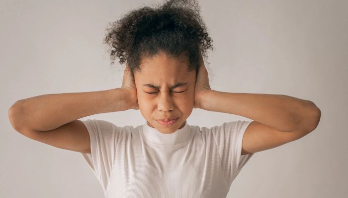 Image shows girl covering ears.— Pexels