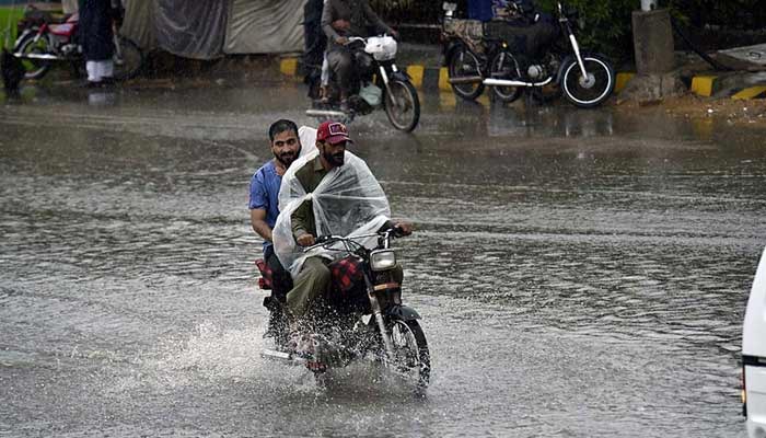 Motorcyclists are passing through a flooded road in Karachi amid heavy rain on September 12, 2022.— APP