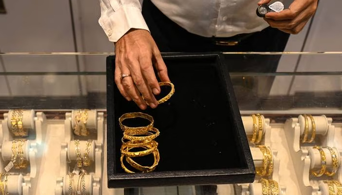 A salesperson displays gold jewellery at a store in this undated file photo. — AFP