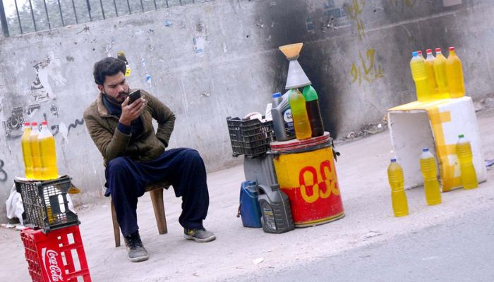 A vendor waits for customers to buy petrol from his roadside setup in Lahore on January 14, 2023. — APP/File