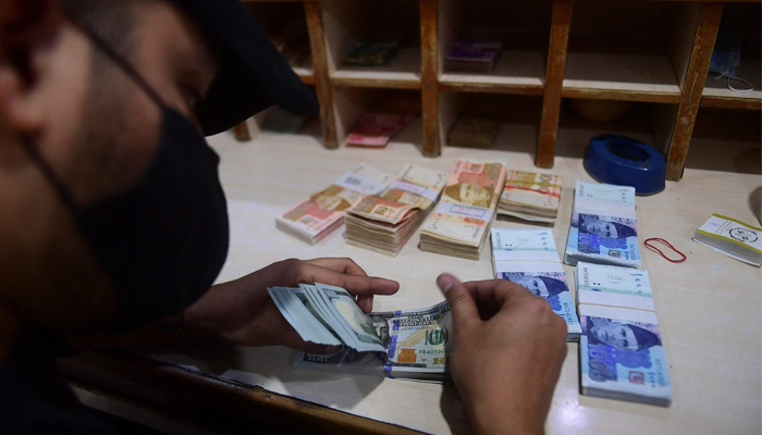A currency exchange dealer counts $100 bills. — AFP/File