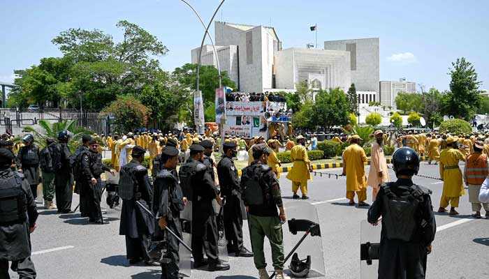 Pakistan'ın iktidar ittifakından partilerin destekçileri 15 Mayıs 2023'te İslamabad'daki Yüksek Mahkeme yakınında toplanırken güvenlik personeli nöbet tutuyor. — AFP