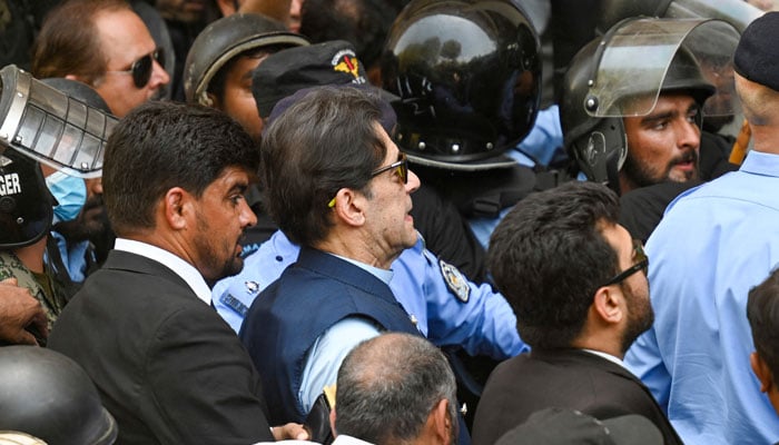 Policemen escort former prime minister Imran Khan (C) as he arrives at the high court in Islamabad on May 12, 2023. — AFP