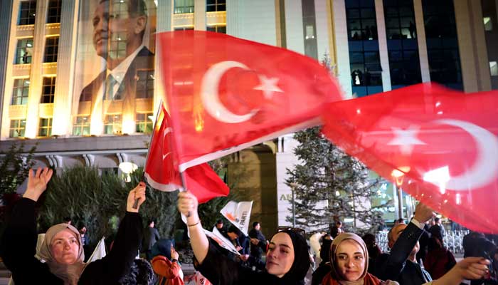 Türkiye Cumhurbaşkanı Recep Tayyip Erdoğan ve AK Parti (AKP) destekçileri, 14 Mayıs 2023'te Ankara'daki AK Parti genel merkezinde bayrak sallıyor. — AFP